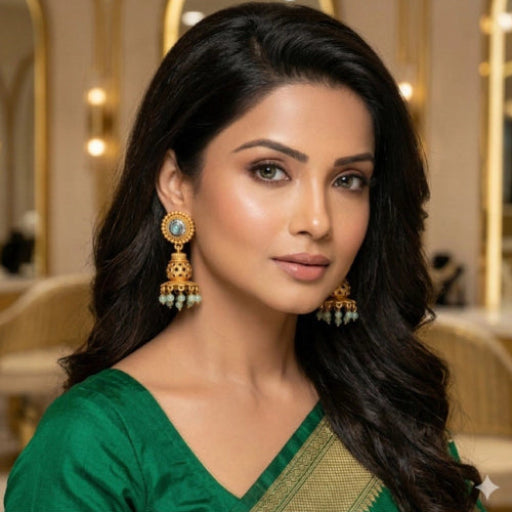 Woman wearing gold earrings with a green blouse in an indoor setting