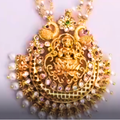 Gold necklace with intricate design and pearl beads on a white background
