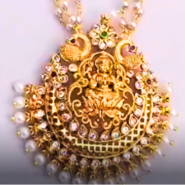 Gold necklace with intricate design and pearl beads on a white background