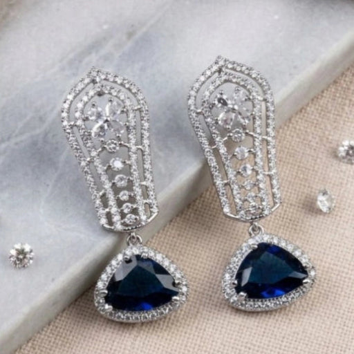 Elegant silver earrings with blue gemstones on a marble surface